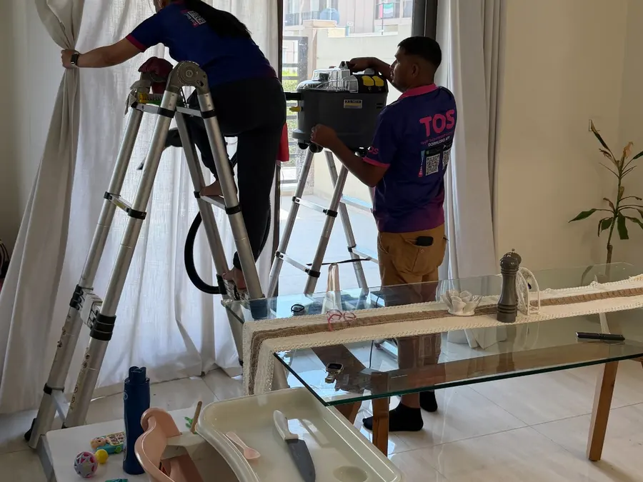 A TopOne cleaner checking curtains at a window