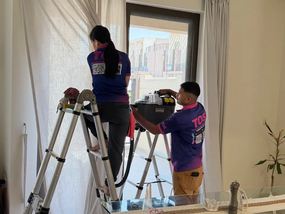 Two TopOne cleaners on ladders cleaning curtains with a steam machine